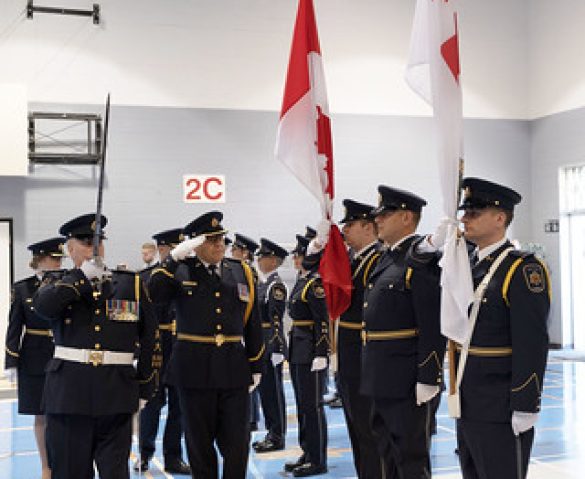 Canadian police officers saluting each other while holding the Canadian flags.