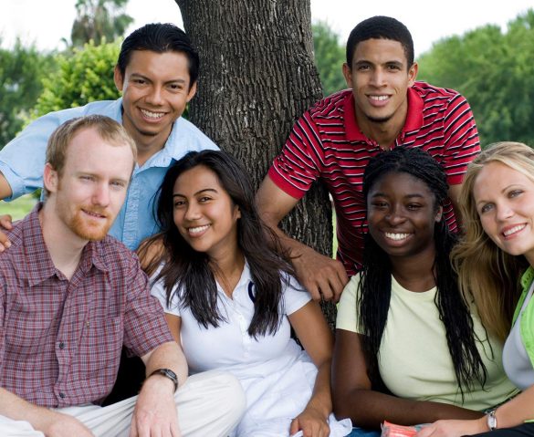Diverse college students smiling in front of a tree