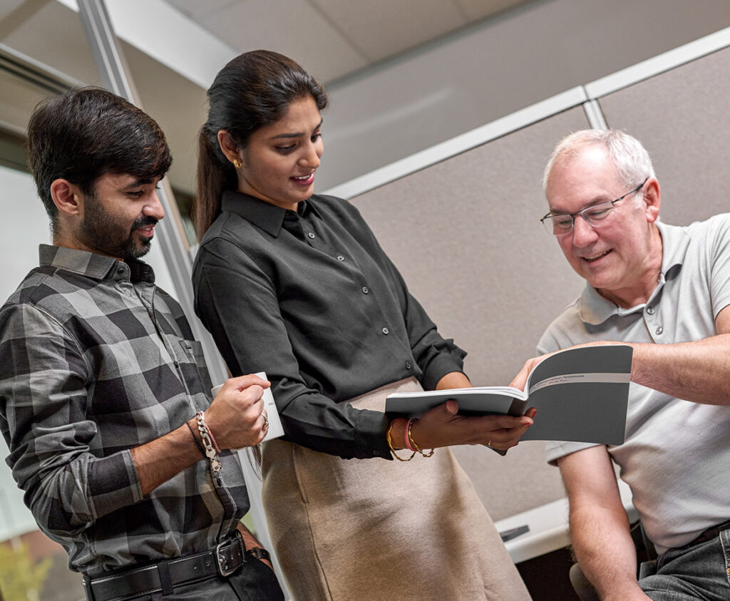 Three professionals analyzing a notebook and working together.